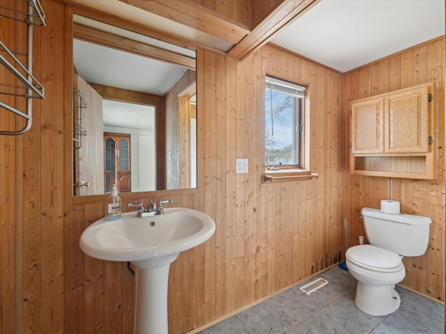 bathroom featuring wooden walls, tile patterned flooring, toilet, and visible vents