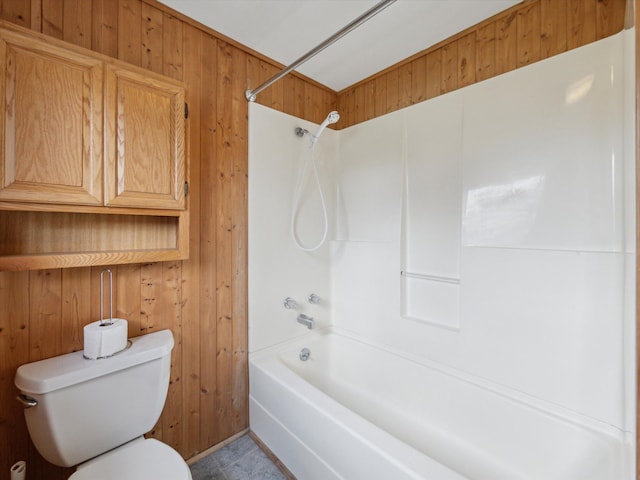 bathroom with wood walls, tub / shower combination, and toilet