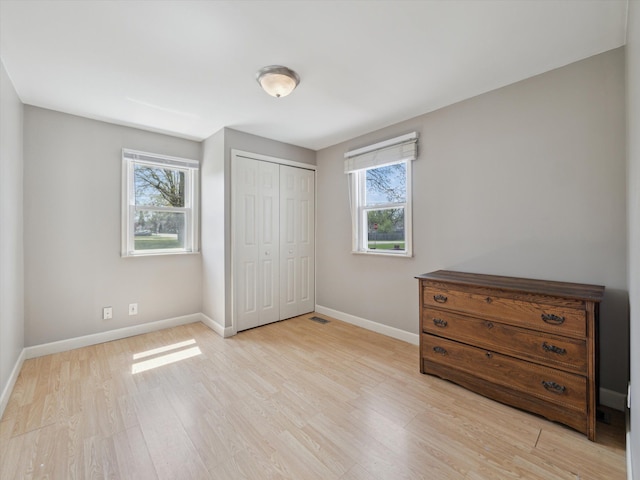 bedroom with a closet, baseboards, and light wood-type flooring
