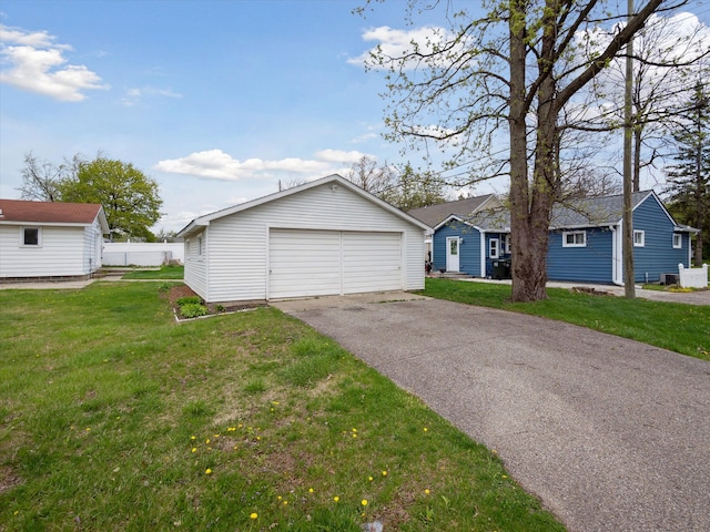 ranch-style home featuring a detached garage, fence, an outbuilding, and a front yard