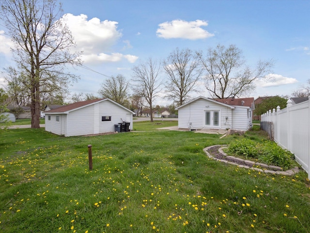 view of yard featuring an outdoor structure, fence, and french doors