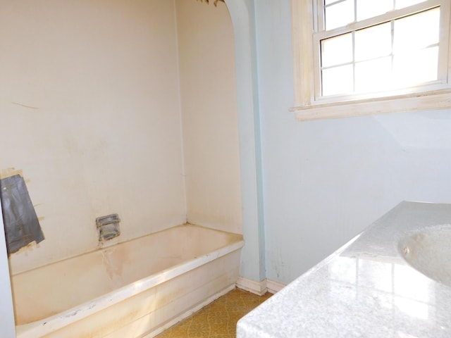 full bath featuring a washtub and baseboards