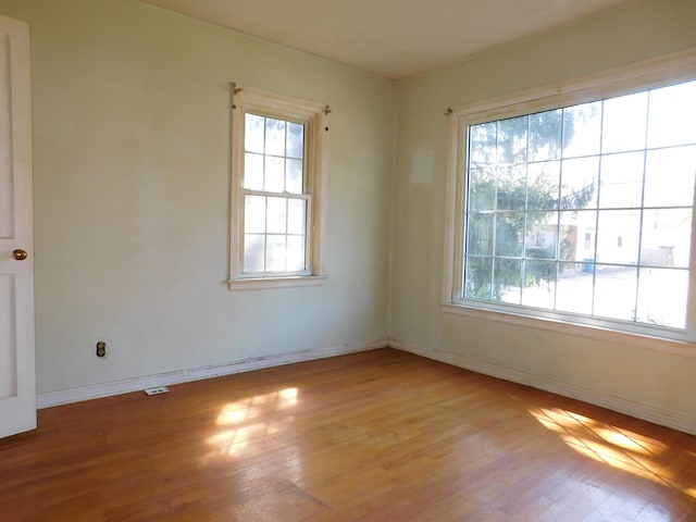 unfurnished room with baseboards, a healthy amount of sunlight, and wood finished floors