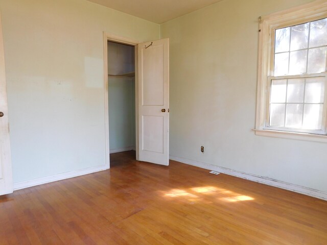 unfurnished bedroom with light wood-style flooring, a closet, baseboards, and multiple windows