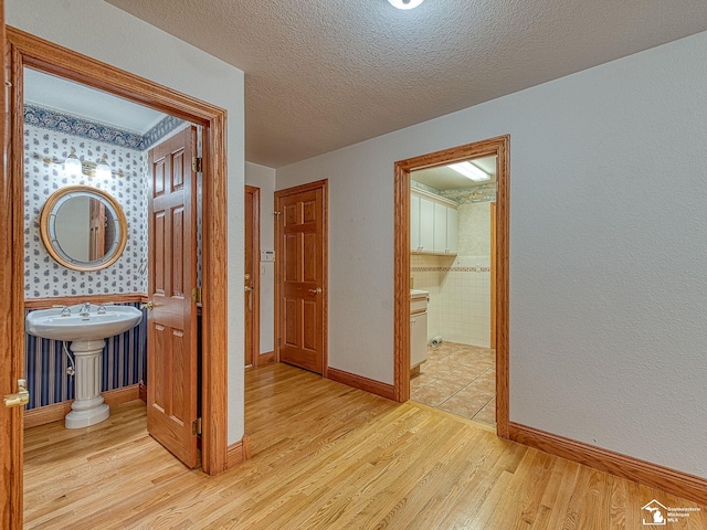 3158 Lennox Ct, Lambertville, MI 48144 - hall featuring light wood finished floors, baseboards, a sink, and a textured ceiling