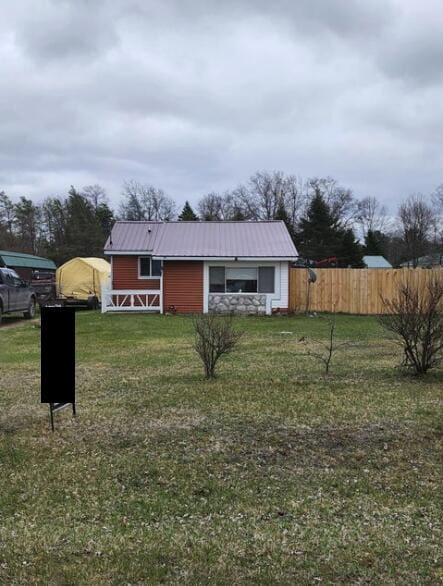 exterior space with a yard, fence, and metal roof