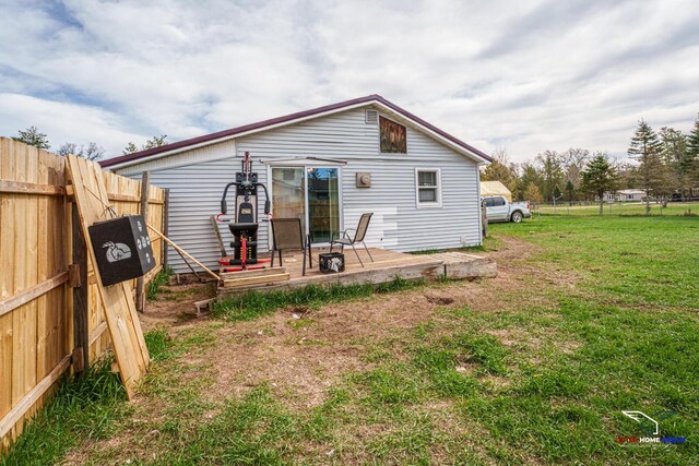 rear view of house featuring fence and a yard
