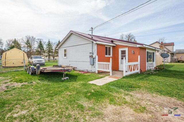 rear view of house with fence and a lawn