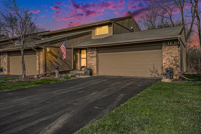 view of front of property with an attached garage, a front lawn, driveway, and brick siding