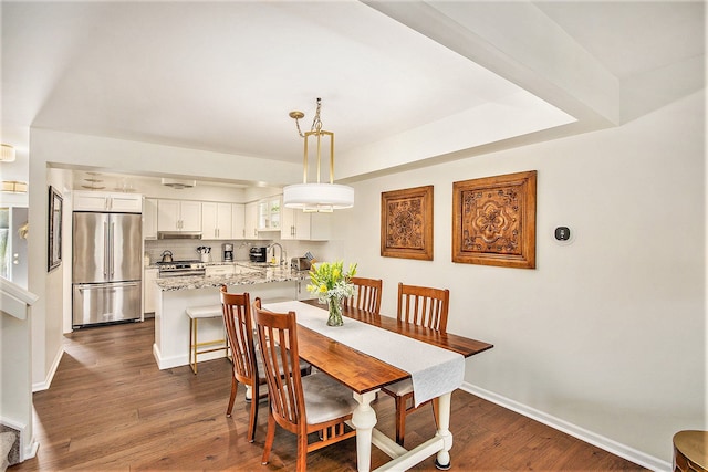 dining space featuring a wealth of natural light, baseboards, and dark wood-style flooring