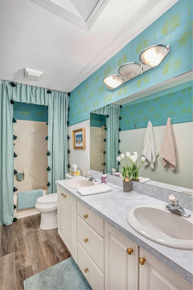 bathroom featuring toilet, a sink, wallpapered walls, and double vanity