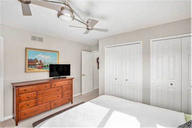 bedroom featuring carpet, visible vents, baseboards, two closets, and ceiling fan