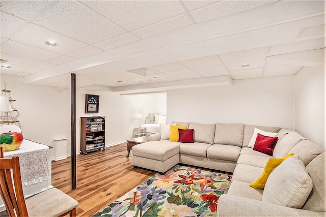 living room with light wood-style floors, a paneled ceiling, and baseboards