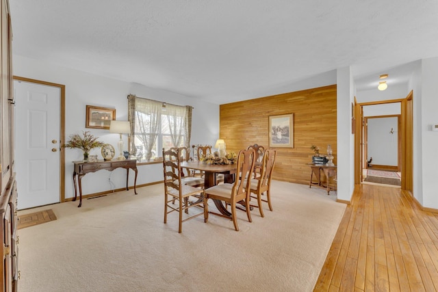 110 Dayton St, Homer, MI 49245 - dining area featuring wooden walls, light wood-type flooring, baseboards, and an accent wall