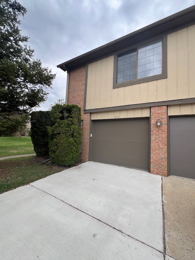 exterior space featuring brick siding, concrete driveway, and an attached garage