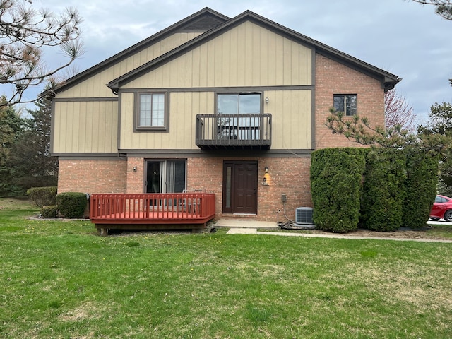rear view of house with a lawn, a deck, central air condition unit, and brick siding