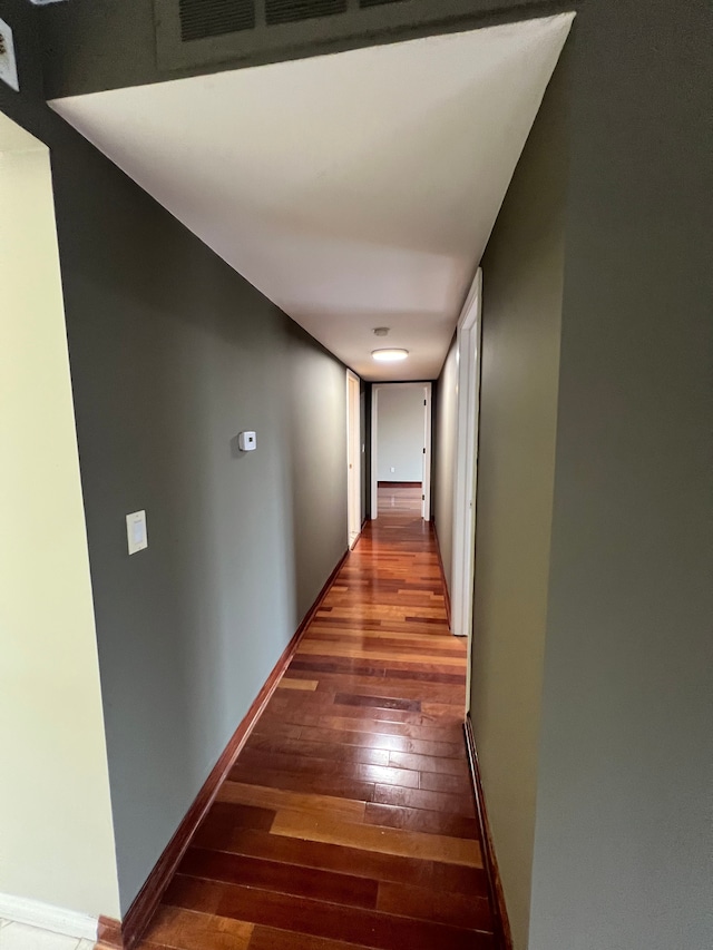 corridor with hardwood / wood-style floors and baseboards