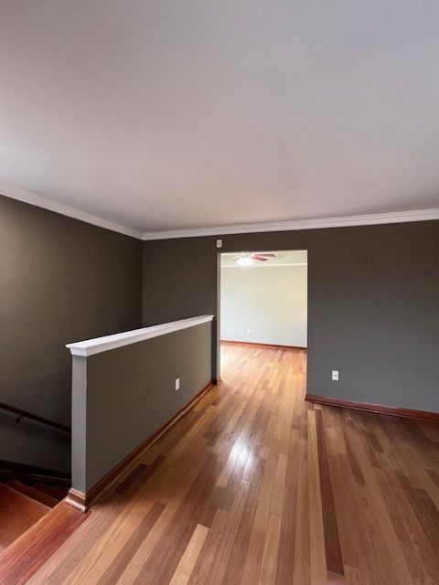 spare room with ornamental molding, wood finished floors, and baseboards