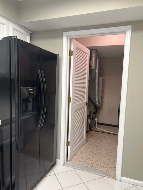 interior space with baseboards, light tile patterned floors, and laundry area
