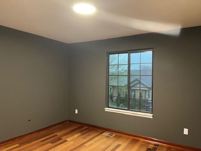 spare room with baseboards, visible vents, and light wood-style floors