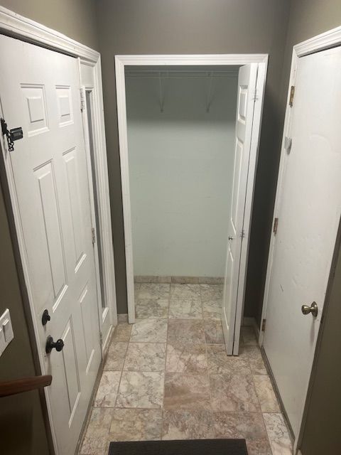 corridor featuring baseboards and stone finish flooring