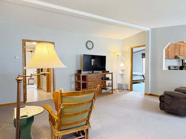 living area featuring baseboards and light carpet