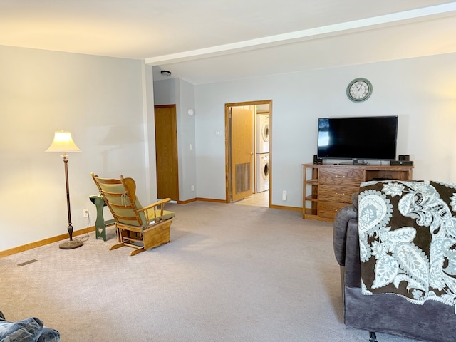 living area with carpet flooring, stacked washer / drying machine, visible vents, and baseboards