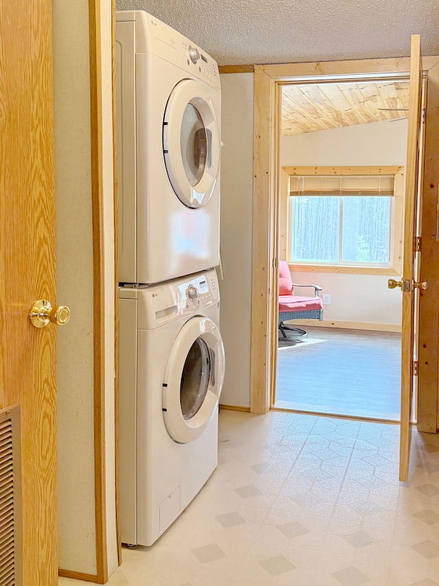 laundry area featuring stacked washer and clothes dryer, tile patterned floors, laundry area, visible vents, and a textured ceiling