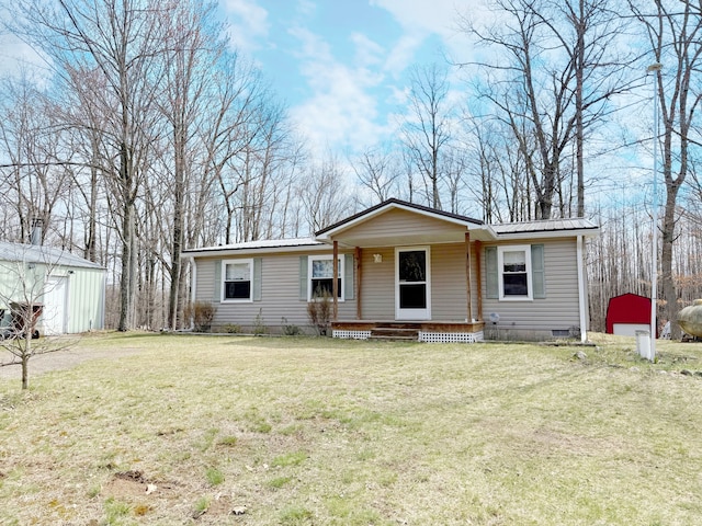 view of front of property featuring metal roof, an outbuilding, crawl space, a porch, and a front lawn