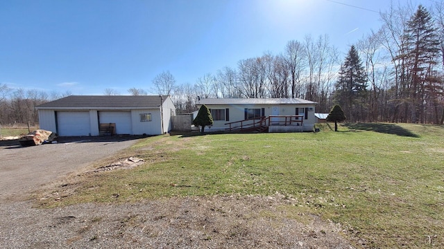 manufactured / mobile home with an outdoor structure, a wooden deck, a front yard, and a garage