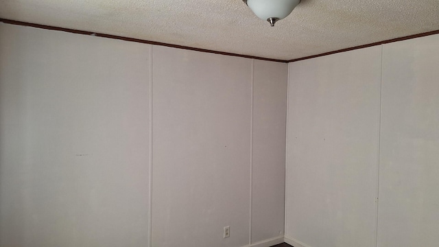 spare room with a textured ceiling, a decorative wall, and crown molding