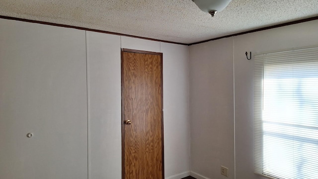 unfurnished room with a textured ceiling, crown molding, and a healthy amount of sunlight