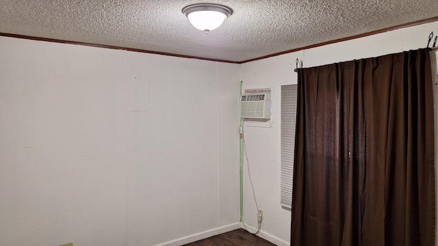 empty room featuring crown molding, a textured ceiling, and dark wood-style floors
