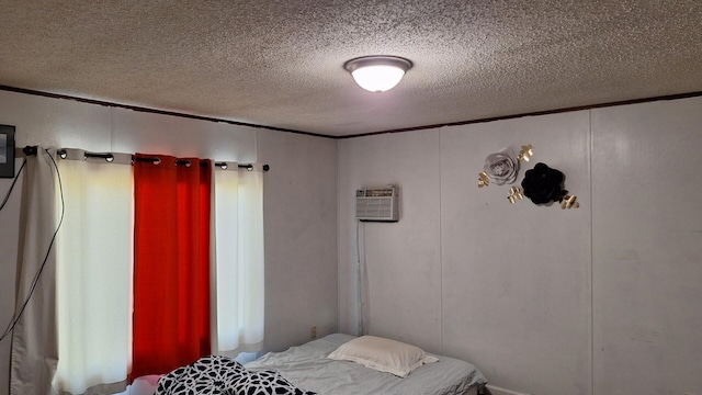 bedroom featuring a decorative wall, a textured ceiling, and a wall mounted AC