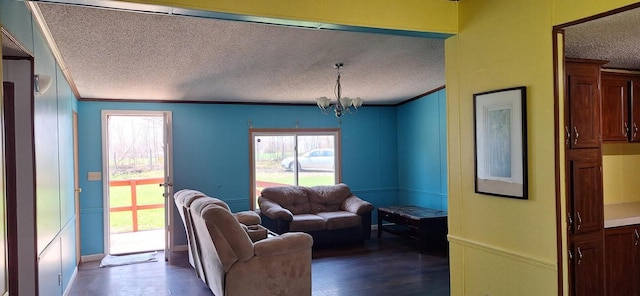living area featuring dark wood-type flooring, a textured ceiling, a notable chandelier, and crown molding