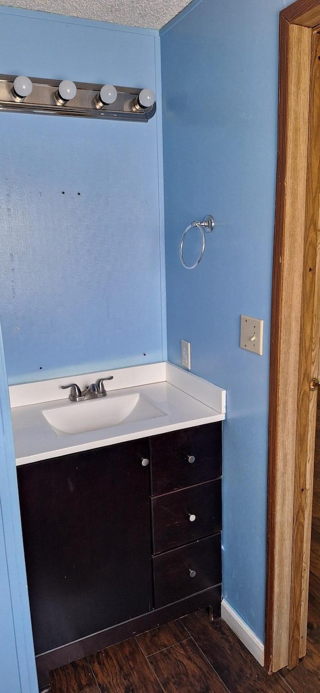 bathroom featuring baseboards, wood finished floors, and vanity