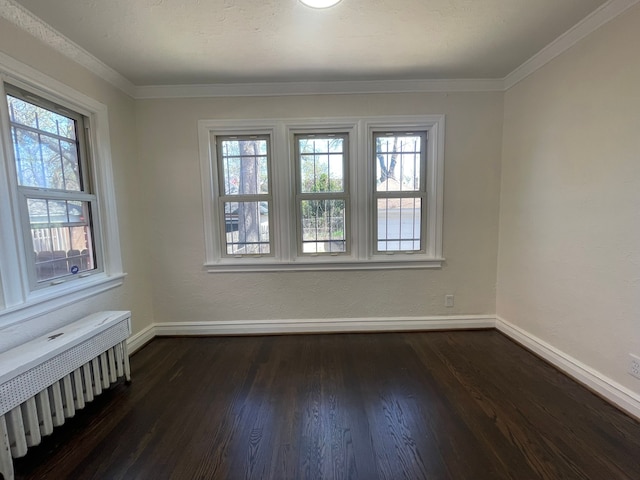 spare room featuring baseboards, dark wood-type flooring, and radiator heating unit
