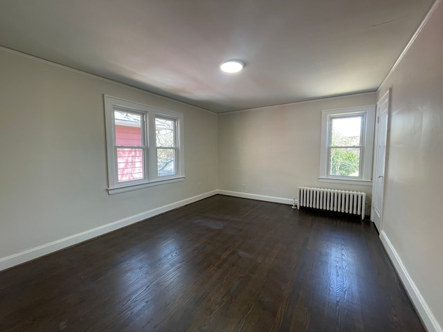 empty room with baseboards, radiator heating unit, and dark wood-type flooring