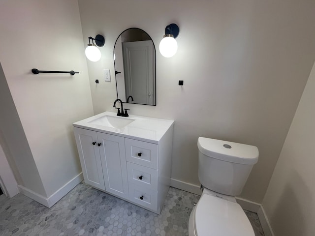 half bath with baseboards, toilet, and vanity
