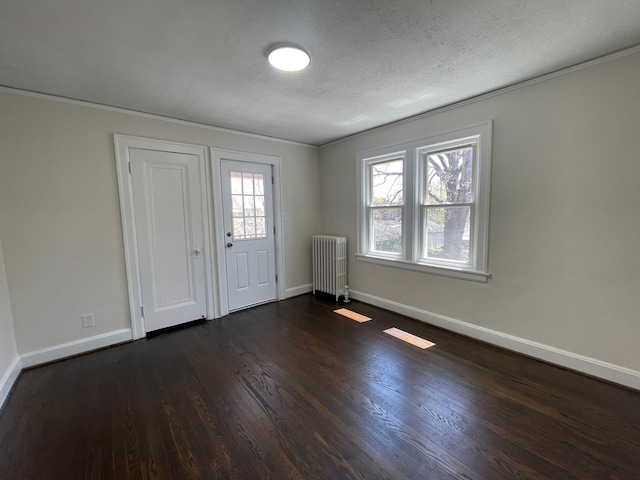 foyer featuring dark wood-style flooring, baseboards, ornamental molding, and radiator