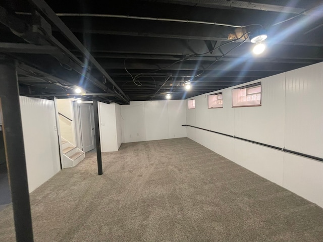 below grade area featuring stairway and light colored carpet