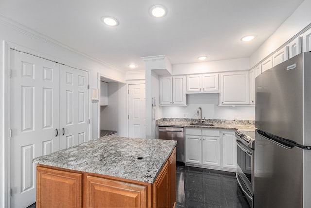 kitchen featuring light stone countertops, appliances with stainless steel finishes, a sink, white cabinetry, and a center island