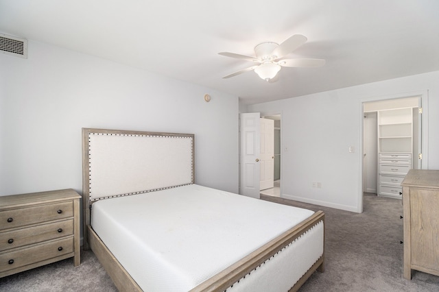 carpeted bedroom featuring a walk in closet, visible vents, ceiling fan, and baseboards
