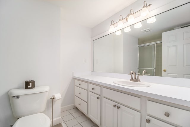 bathroom with vanity, toilet, a stall shower, baseboards, and tile patterned flooring