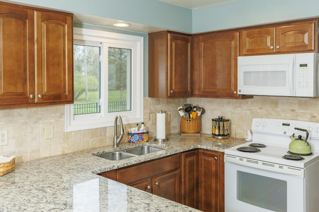 11630 Mcclumpha Rd, Plymouth, MI 48170 - kitchen with light stone counters, white appliances, brown cabinetry, and a sink