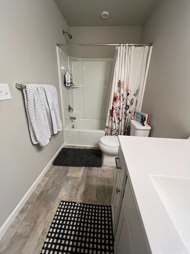 full bath featuring vanity, wood finished floors, toilet, baseboards, and shower / tub combo