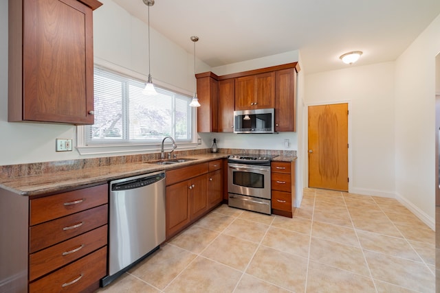 kitchen featuring brown cabinetry, hanging light fixtures, a sink, stainless steel appliances, and light tile patterned flooring