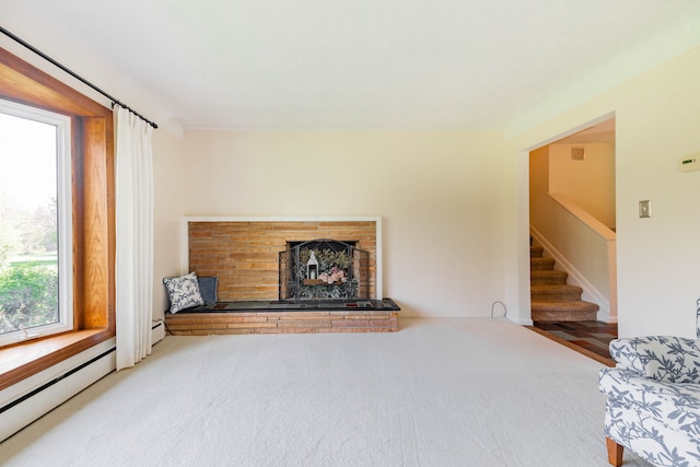 unfurnished living room featuring a brick fireplace, carpet flooring, a baseboard heating unit, and stairway
