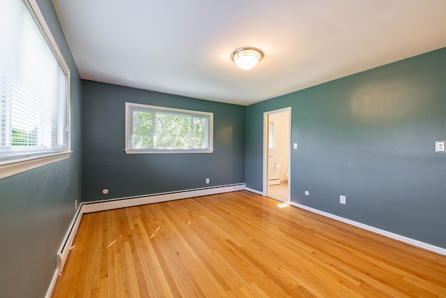spare room featuring baseboard heating, baseboards, a baseboard heating unit, and wood finished floors