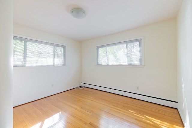 empty room with light wood-style floors, baseboards, and a baseboard heating unit